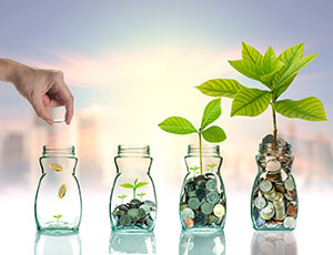Hand dropping coins into jar to grow savings