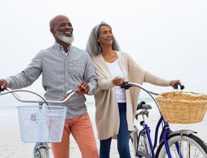 Man and woman at the beach standing with their bikes and smiling